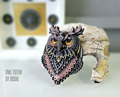 an owl figurine sitting on top of a table next to a piece of art