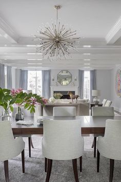 a dining room table with white chairs and a chandelier