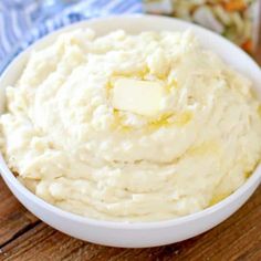 a white bowl filled with mashed potatoes on top of a wooden table