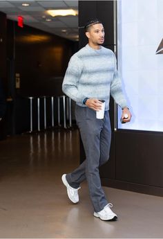 a man in grey sweater and white sneakers walking