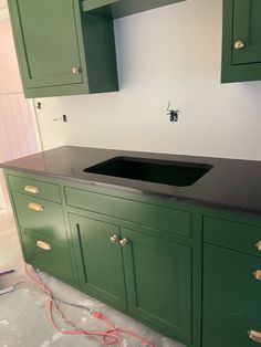 a kitchen with green cabinets and a black sink