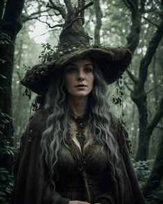 a woman with long gray hair wearing a green hat and dress in the woods,