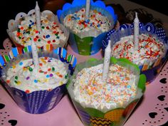 four cupcakes with candles in them on a table