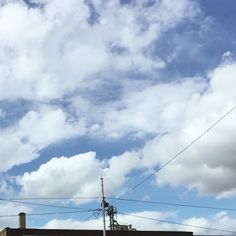 a street sign on the side of a building with clouds in the sky behind it