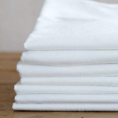 a stack of folded white sheets sitting on top of a wooden table