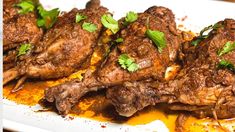 some meat is on a white plate and garnished with cilantro leaves