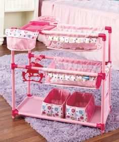 a child's bedroom with pink furniture and accessories on the floor, including a toy crib