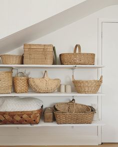 baskets and baskets are arranged on the shelves in this white room with stairs leading up to the second floor