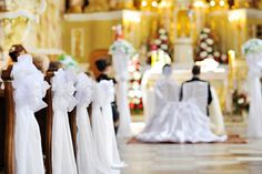 rows of chairs with white sashes and bows on them in front of a church alter