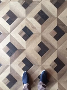 a person standing on top of a wooden floor next to a tiled floor with black and white squares