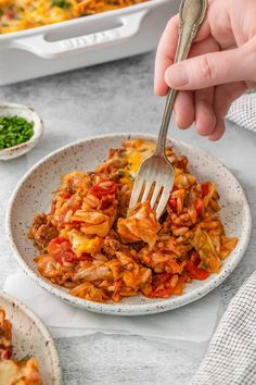 a person holding a fork over a bowl of food with other dishes in the background