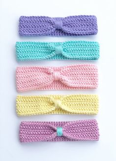 four crocheted headbands with bows on them, all in pastel colors