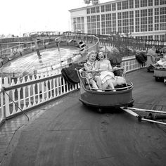 two women are riding on a roller coaster at an amusement park in black and white