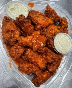 a plastic container filled with chicken wings covered in sauce