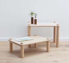 two wooden tables sitting on top of a hard wood floor next to a plant in a vase