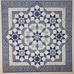 a blue and white quilt with an intricate design on the center, surrounded by stars