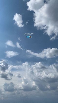 two people on the beach flying kites under a cloudy blue sky with white clouds