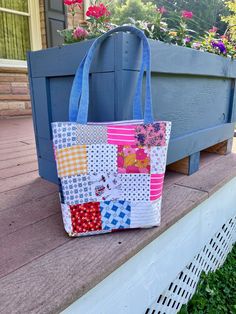 a handbag sitting on top of a blue bench next to some flowers and bushes