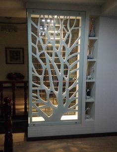 an open door with a tree design on the side and shelves behind it in a living room