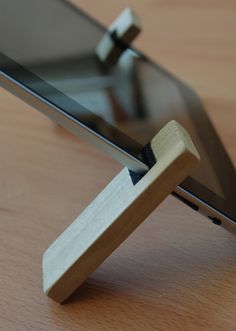 a tablet with a wooden stand attached to it's side on a wood table