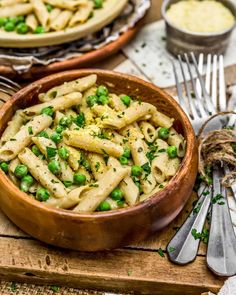 a wooden bowl filled with pasta and peas