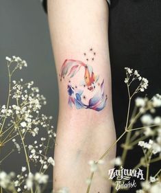 a woman's arm with a tattoo on it that has an image of a fish and stars