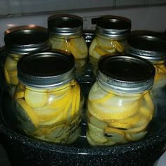 several jars filled with pickles sitting on top of a stove