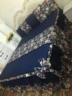 a bed covered in blue floral sheets and pillows