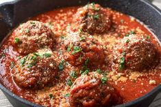 meatballs in tomato sauce with parsley in a cast iron skillet on a table