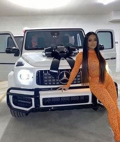 a woman sitting on the hood of a white mercedes benz truck with a black ribbon around her neck