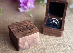 a wooden box with a wedding ring in it sitting on a table next to flowers