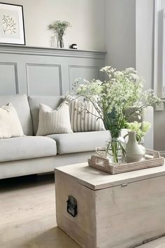 a living room filled with furniture and flowers on top of a coffee table in front of a window