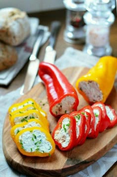 several stuffed peppers on a cutting board with bread in the background