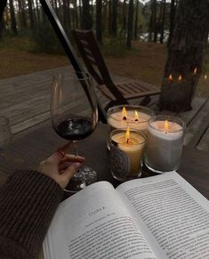 an open book sitting on top of a wooden table next to two glasses of wine