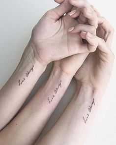 two people with matching tattoos on their arms holding hands and the other hand has writing on it