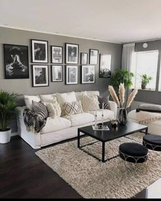 a living room filled with white furniture and pictures on the wall above it's coffee table