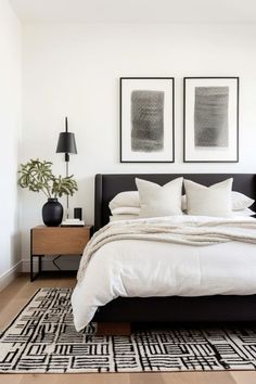 a bedroom with white walls, black and white bedding and pictures on the wall