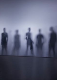 a group of people standing in front of a foggy wall with one person holding an umbrella