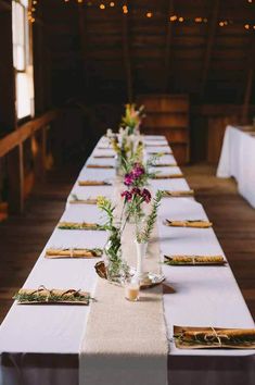 a long table is set with place settings and flowers