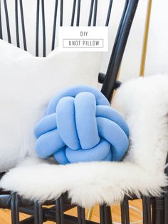 a blue knot pillow sitting on top of a black chair next to a white pillow