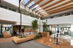 the inside of an office building with wooden floors and plants on display in the center