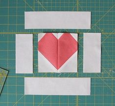 a piece of paper with a red heart on it next to scissors and cutting mat