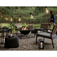 an outdoor fire pit surrounded by chairs and lights