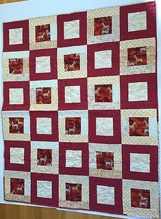 a red and white quilt hanging on a wall next to a wooden table topper