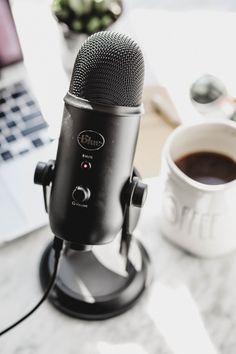 a microphone sitting on top of a table next to a laptop computer and cup of coffee