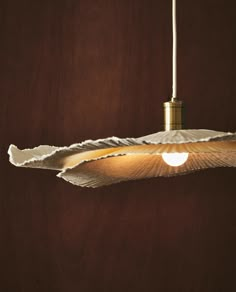 a light hanging from a wooden ceiling with paper on it's side and two lights in the middle