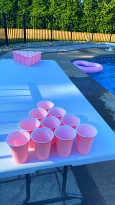 plastic cups are lined up on a table next to a pool