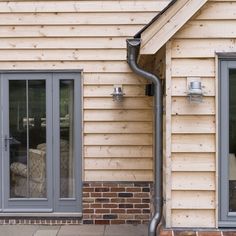 an outside view of a house that is being built with wood siding and metal pipes