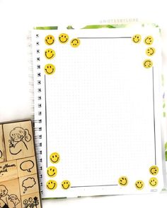 a notebook with smiley faces on it next to a rubber stamp and some other items