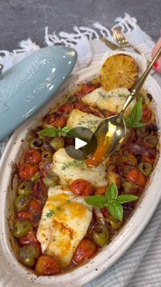 a white bowl filled with food on top of a table next to a blue spoon